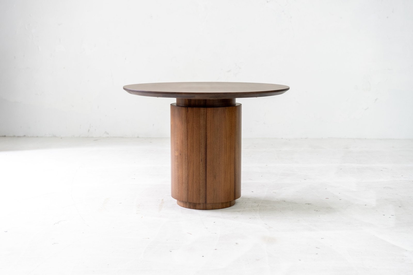 Circular tabletop with pedestal base and wood grain visible along the edges.